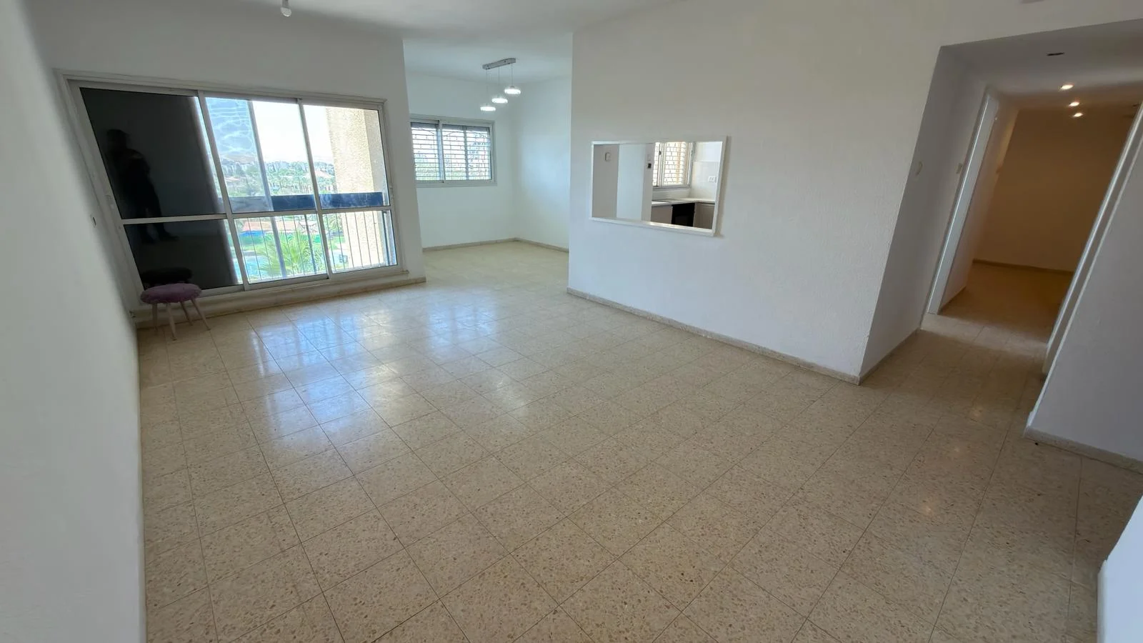 פנים דירה מרווחת עם סלון מואר, חלונות גדולים וריצוף טרצו