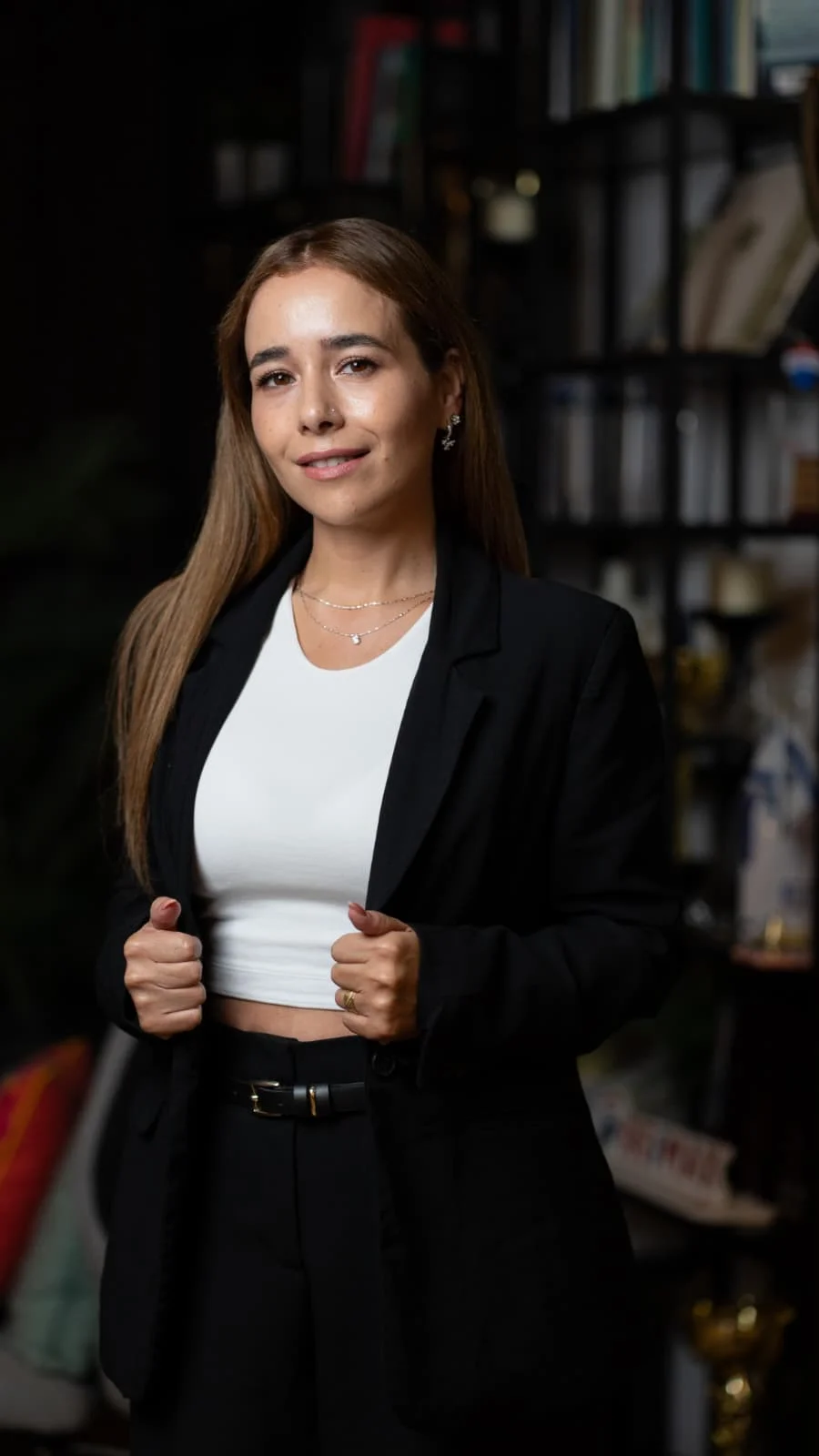 טוני בוהדנה בחליפה שחורה, מחייכת ומחזיקה את דש החליפה.