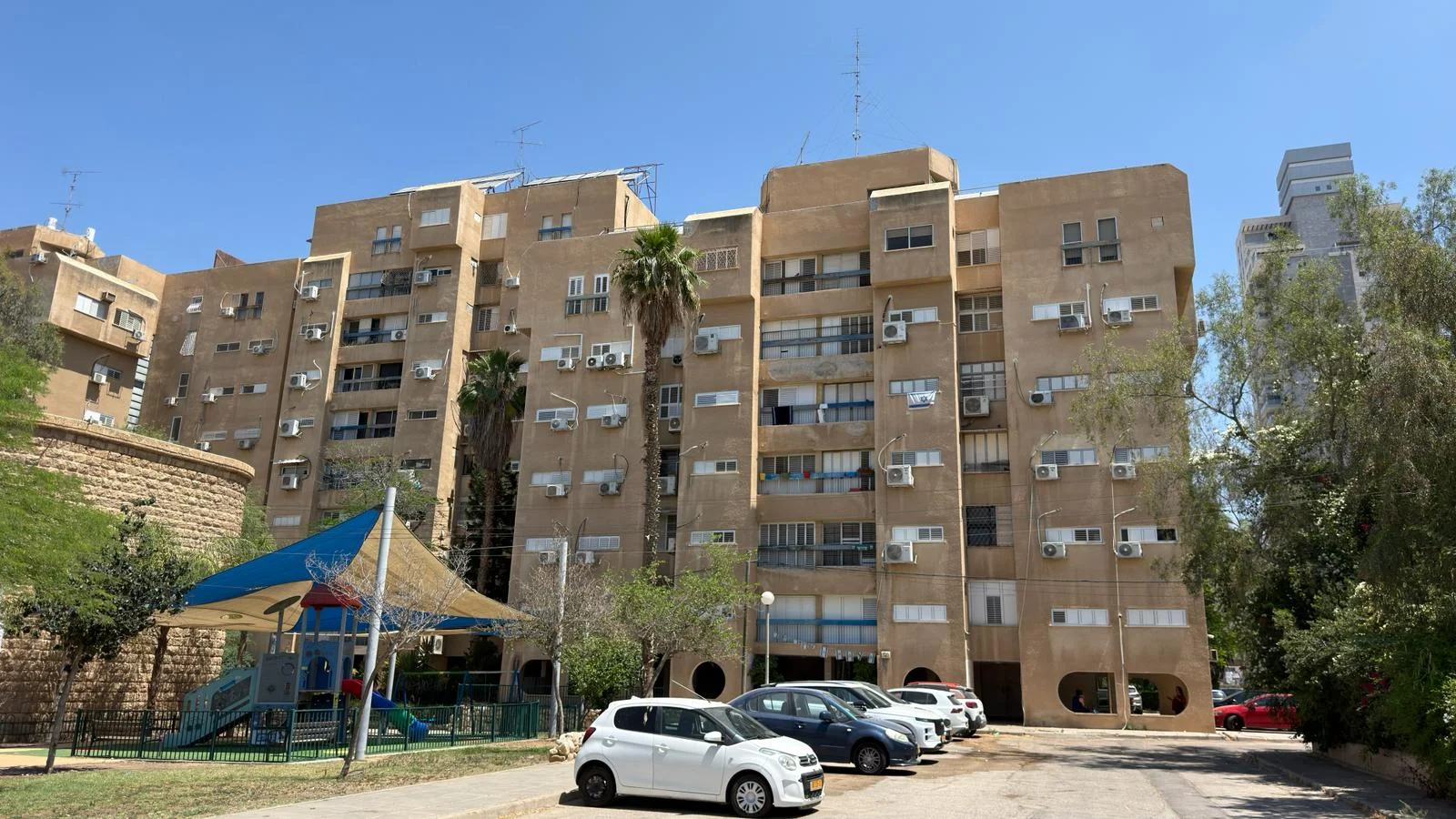 בניין מגורים בן מספר קומות בבאר שבע, עם גינת משחקים לילדים בחזית
